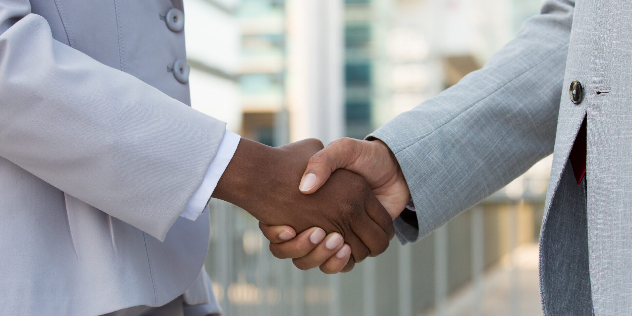 Multiethnic leaders greeting each other in city. Closeup of business man and woman shaking hands outside. Cooperation concept